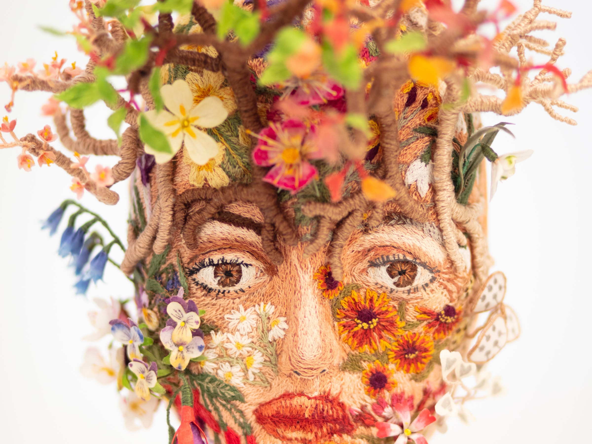 Needlepainted face with silk flowers