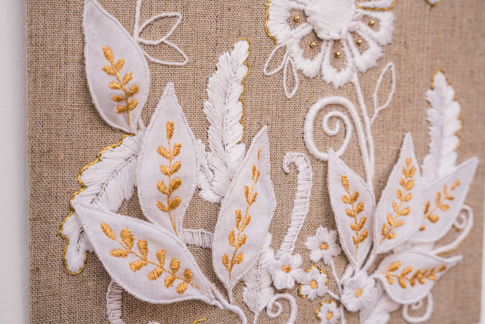 Whitework leaves and gold sprigs raised from the linen